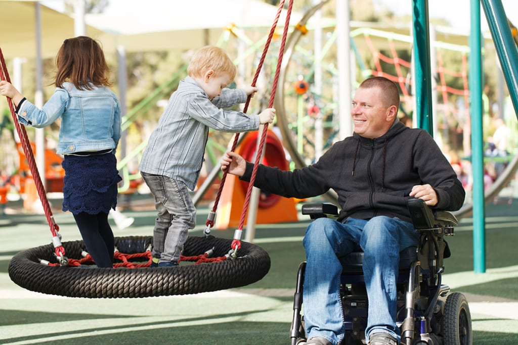 Man in wheel chair at park with child