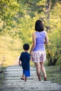 Woman and boy walking path outside. 