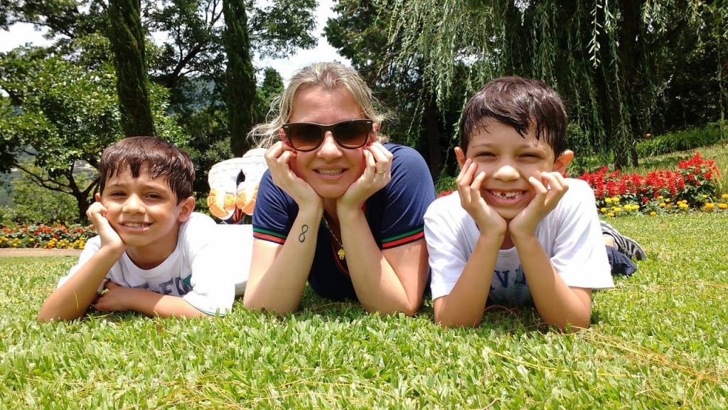 three kids laying on grass smiling